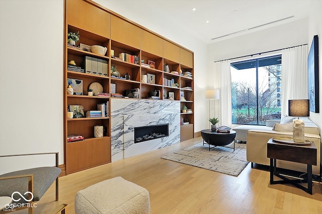 living area featuring a premium fireplace, built in shelves, and light hardwood / wood-style flooring