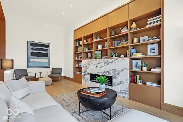 sitting room featuring a high end fireplace, built in features, and light wood-type flooring