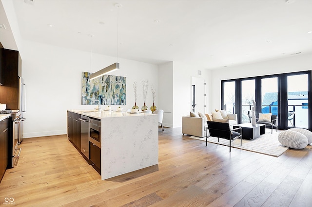 kitchen with sink, a center island, pendant lighting, stainless steel appliances, and light hardwood / wood-style floors