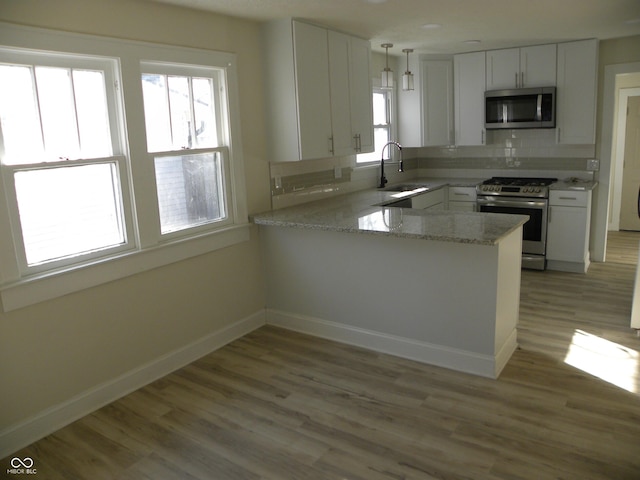 kitchen featuring appliances with stainless steel finishes, kitchen peninsula, sink, and white cabinets