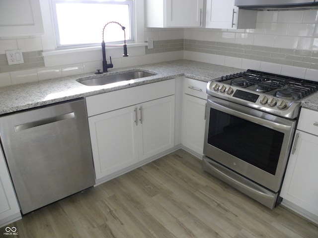 kitchen with stainless steel appliances, tasteful backsplash, sink, and white cabinetry