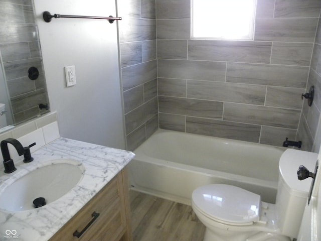 full bathroom with vanity, tiled shower / bath, hardwood / wood-style floors, and toilet