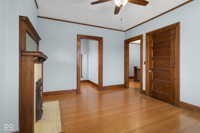 1023 Franklin St, Columbus, IN 47201 - unfurnished living room with ceiling fan, ornamental molding, a fireplace, and light hardwood / wood-style flooring