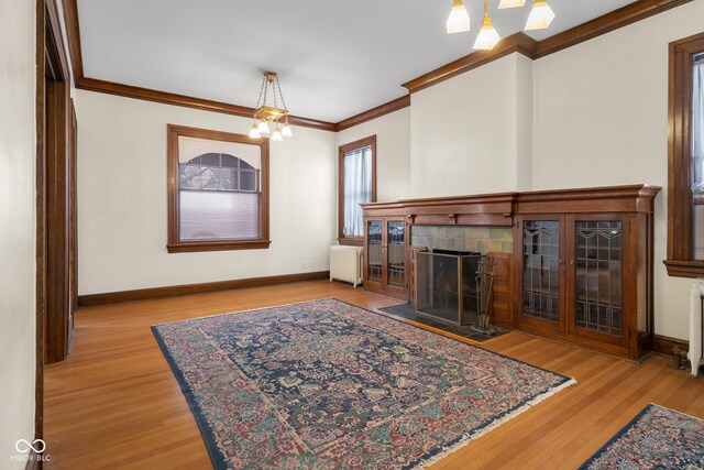 1023 Franklin St, Columbus, IN 47201 - living room with light hardwood / wood-style floors, radiator heating unit, crown molding, and an inviting chandelier