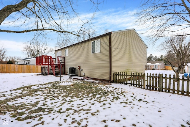 snow covered rear of property featuring cooling unit and a wooden deck