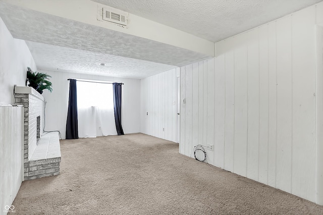 carpeted empty room featuring a textured ceiling, a fireplace, and wood walls