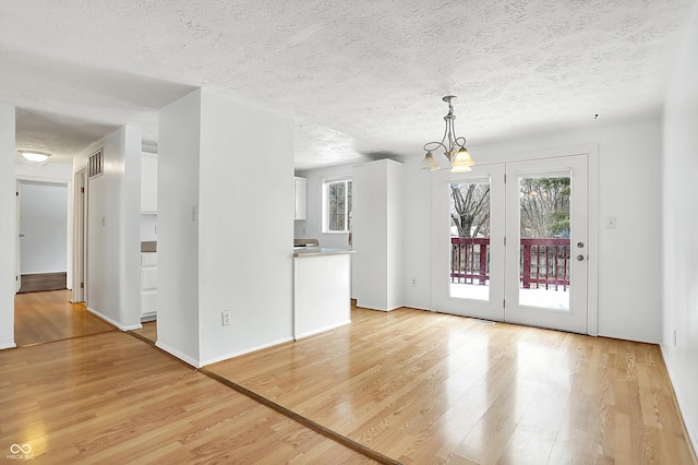 interior space with an inviting chandelier, a textured ceiling, and light wood-type flooring