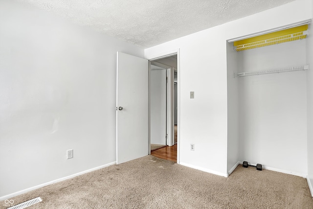 unfurnished bedroom featuring a closet, a textured ceiling, and carpet flooring