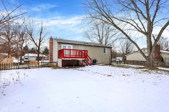 snow covered house with a wooden deck and central AC unit