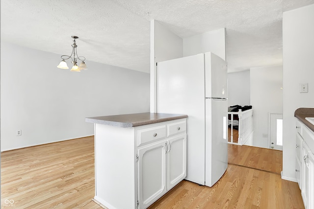 kitchen with pendant lighting, white cabinetry, white refrigerator, light hardwood / wood-style floors, and a textured ceiling