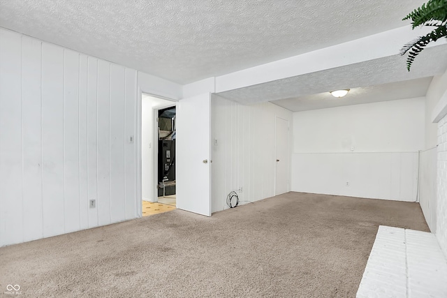 unfurnished room featuring wood walls, a textured ceiling, and carpet flooring