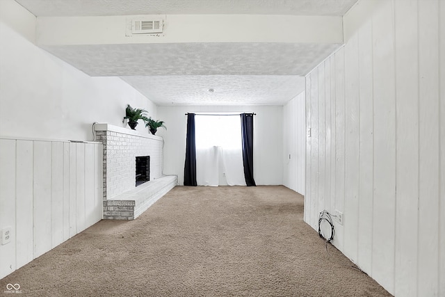 unfurnished living room with a fireplace, wooden walls, light colored carpet, and a textured ceiling