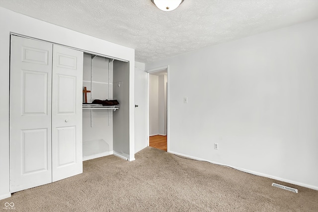 unfurnished bedroom with carpet, a closet, and a textured ceiling