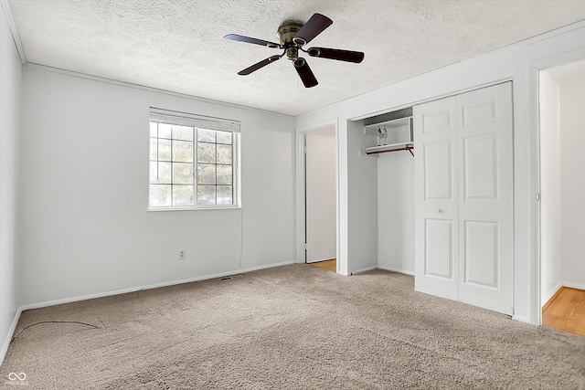 unfurnished bedroom featuring light carpet, a textured ceiling, a closet, and ceiling fan