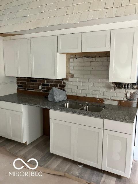 kitchen with hardwood / wood-style flooring, sink, white cabinets, and dark stone countertops