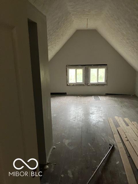 additional living space featuring a textured ceiling and vaulted ceiling