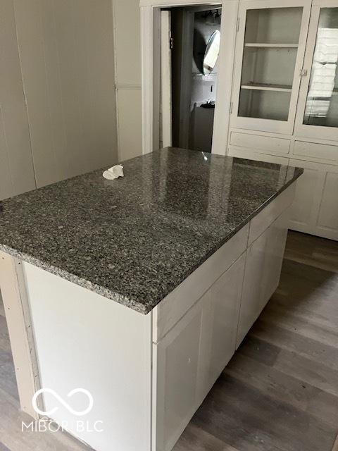 kitchen with dark wood-type flooring, white cabinetry, a center island, and dark stone countertops