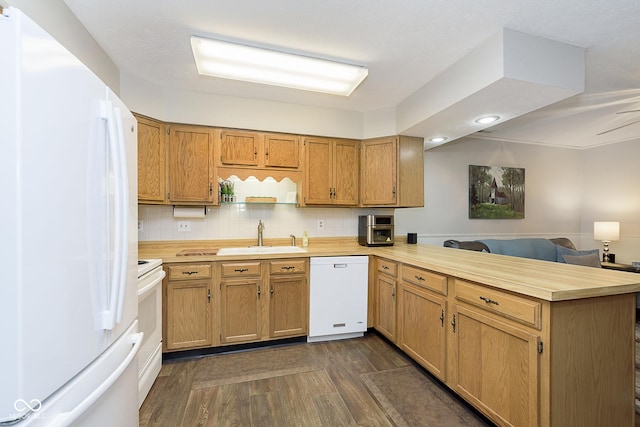 kitchen with sink, white appliances, tasteful backsplash, dark hardwood / wood-style flooring, and kitchen peninsula