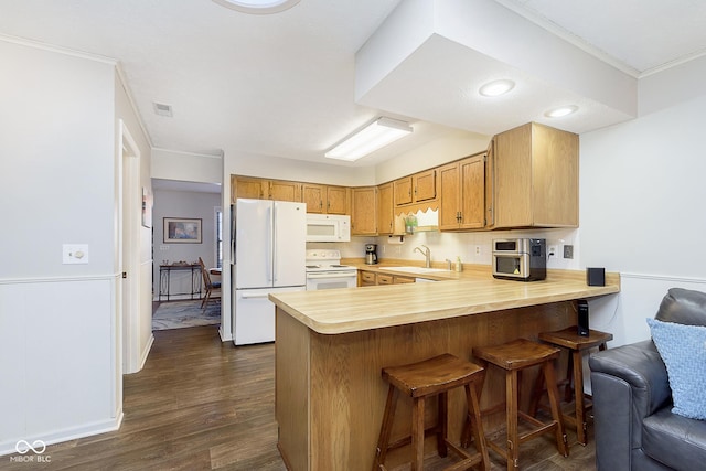 kitchen with sink, dark wood-type flooring, white appliances, and kitchen peninsula