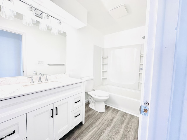 full bathroom with hardwood / wood-style flooring, washtub / shower combination, toilet, and vanity