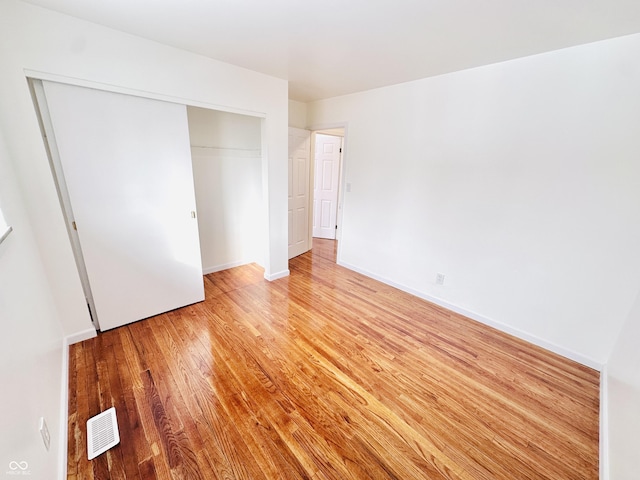 unfurnished bedroom with light wood-type flooring and a closet