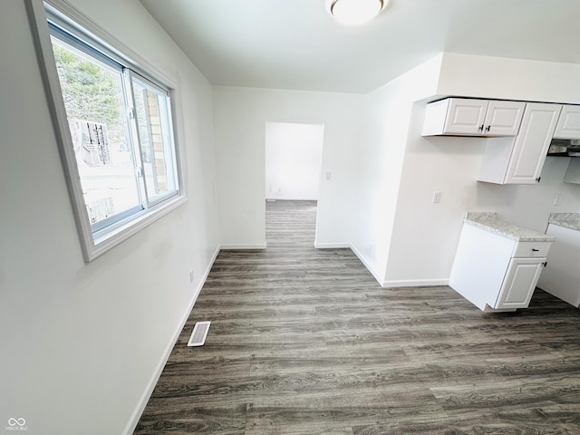 interior space featuring white cabinetry, dark hardwood / wood-style flooring, and light stone counters