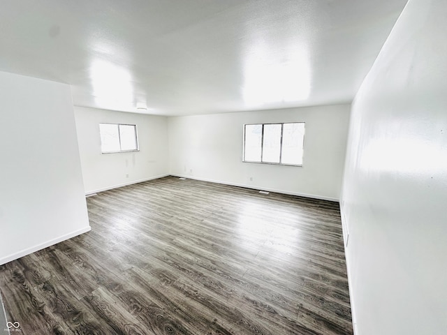 spare room featuring dark wood-type flooring and plenty of natural light