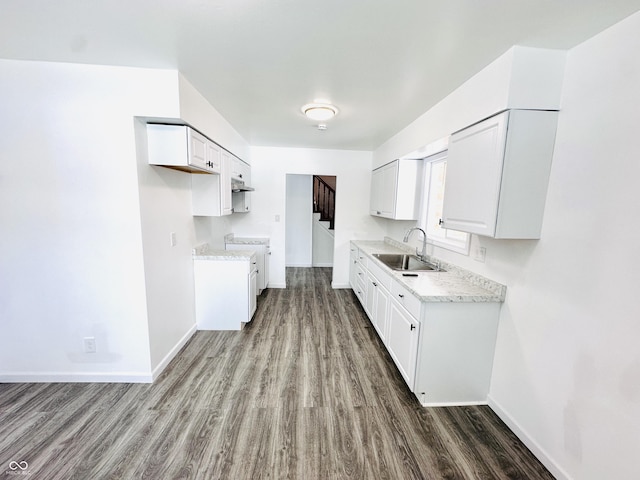 kitchen featuring white cabinets, range, sink, hardwood / wood-style flooring, and light stone counters