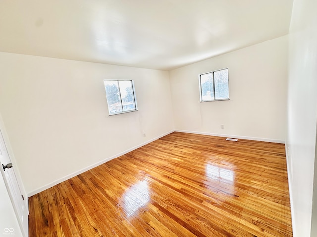 spare room featuring plenty of natural light and light hardwood / wood-style flooring