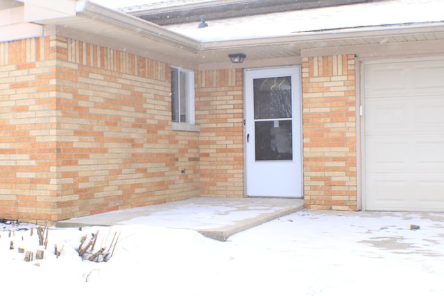 snow covered property entrance with a garage