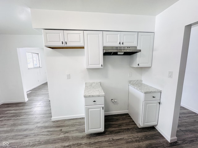 kitchen with light stone countertops, white cabinets, and dark hardwood / wood-style flooring