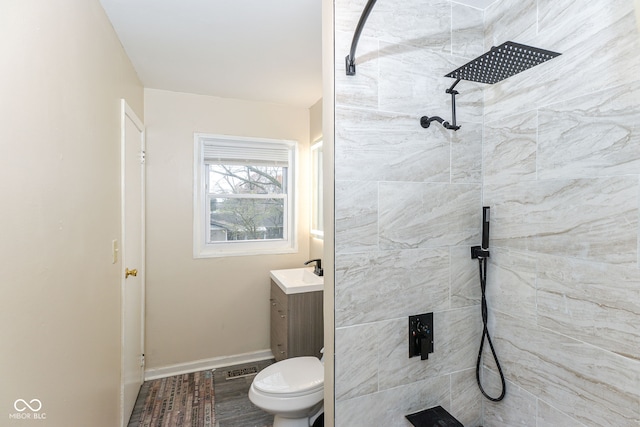 bathroom featuring wood-type flooring, tiled shower, vanity, and toilet