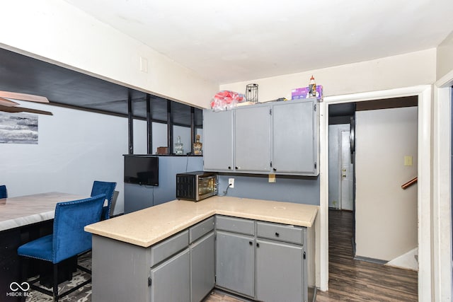 kitchen featuring dark hardwood / wood-style floors, gray cabinetry, and kitchen peninsula