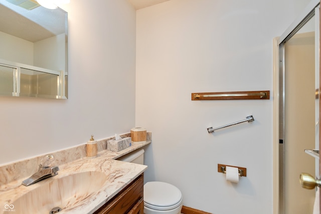 bathroom featuring vanity, an enclosed shower, and toilet