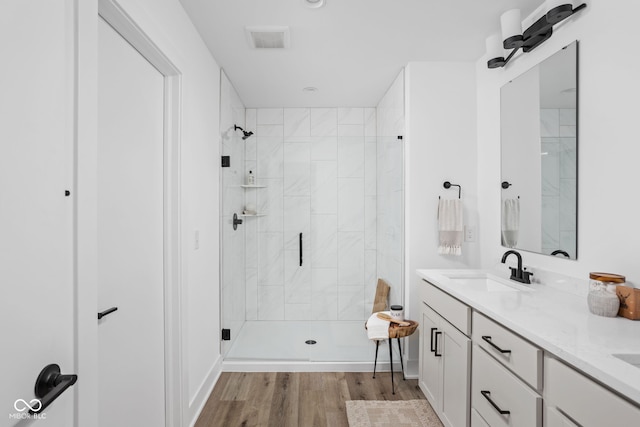 bathroom featuring hardwood / wood-style flooring, a shower with shower door, and vanity