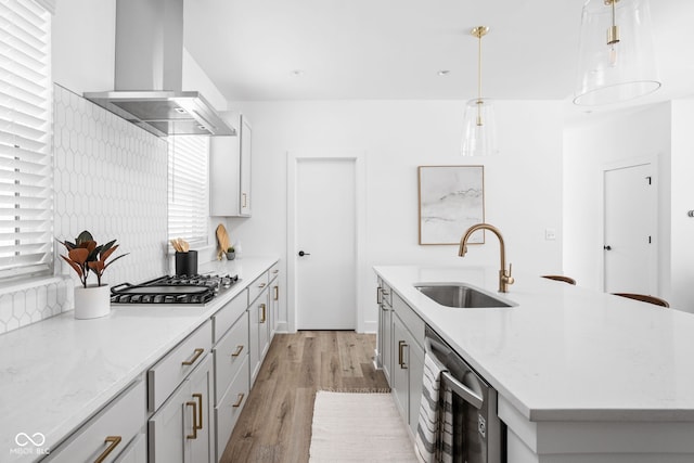 kitchen with stainless steel gas cooktop, island exhaust hood, a kitchen island with sink, sink, and pendant lighting