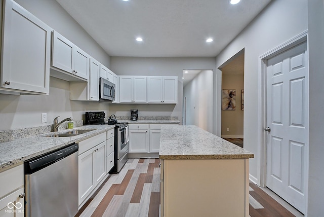 kitchen featuring white cabinetry, sink, a center island, light hardwood / wood-style floors, and stainless steel appliances