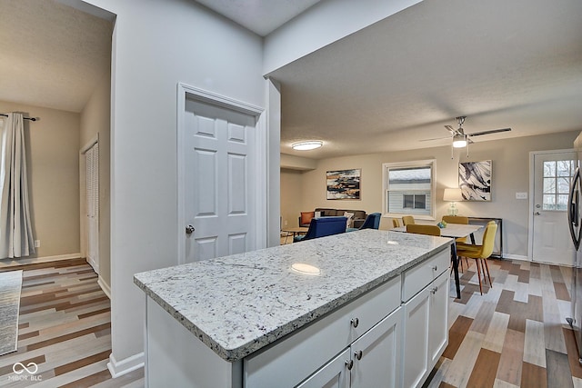 kitchen with a kitchen island, a healthy amount of sunlight, white cabinets, and light hardwood / wood-style flooring