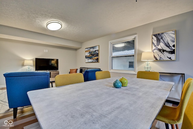 dining space featuring wood-type flooring and a textured ceiling