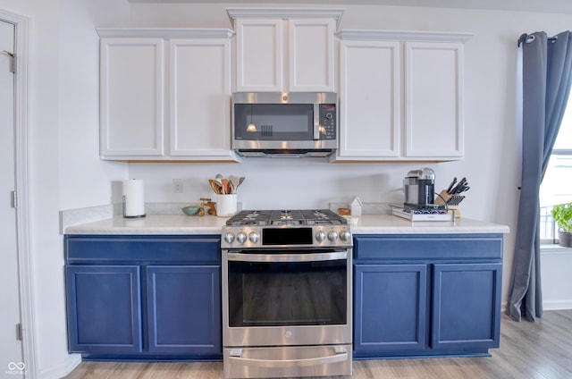 kitchen with light hardwood / wood-style floors, blue cabinetry, white cabinetry, and stainless steel appliances