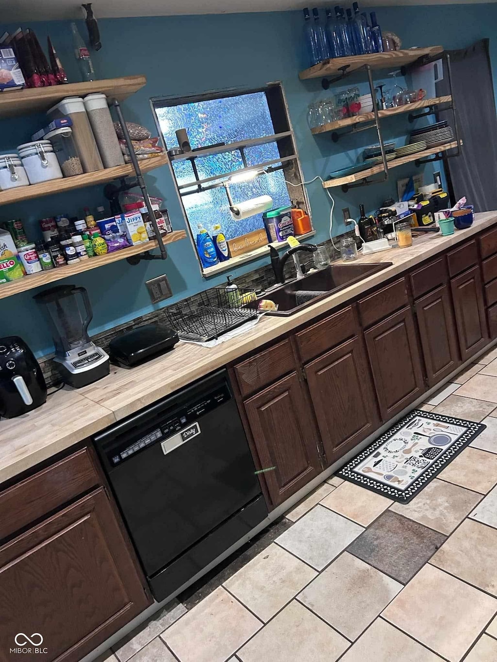 kitchen with light tile patterned flooring, dishwasher, sink, and dark brown cabinets