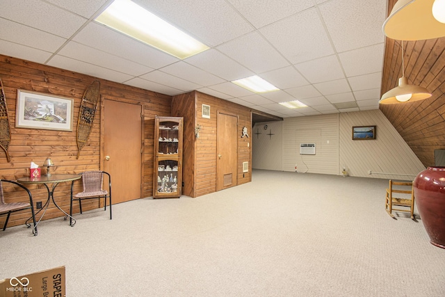 sitting room with carpet, a paneled ceiling, and wood walls