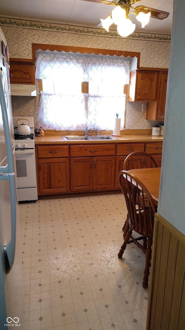 kitchen with white gas range, sink, refrigerator, and decorative backsplash