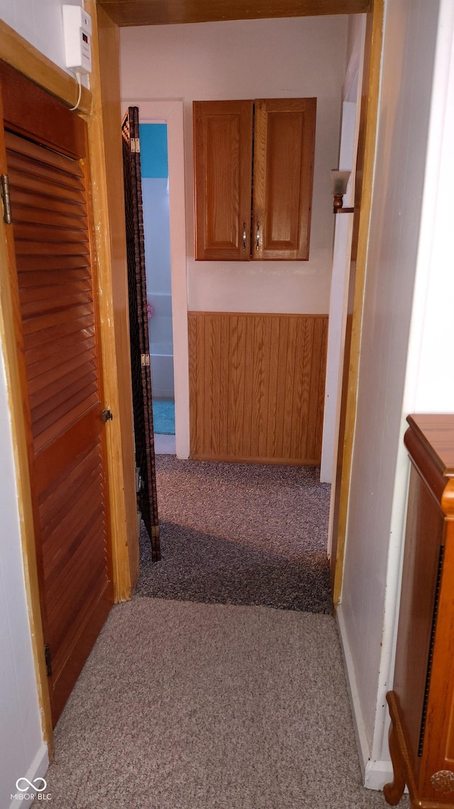 hallway with carpet floors and wooden walls