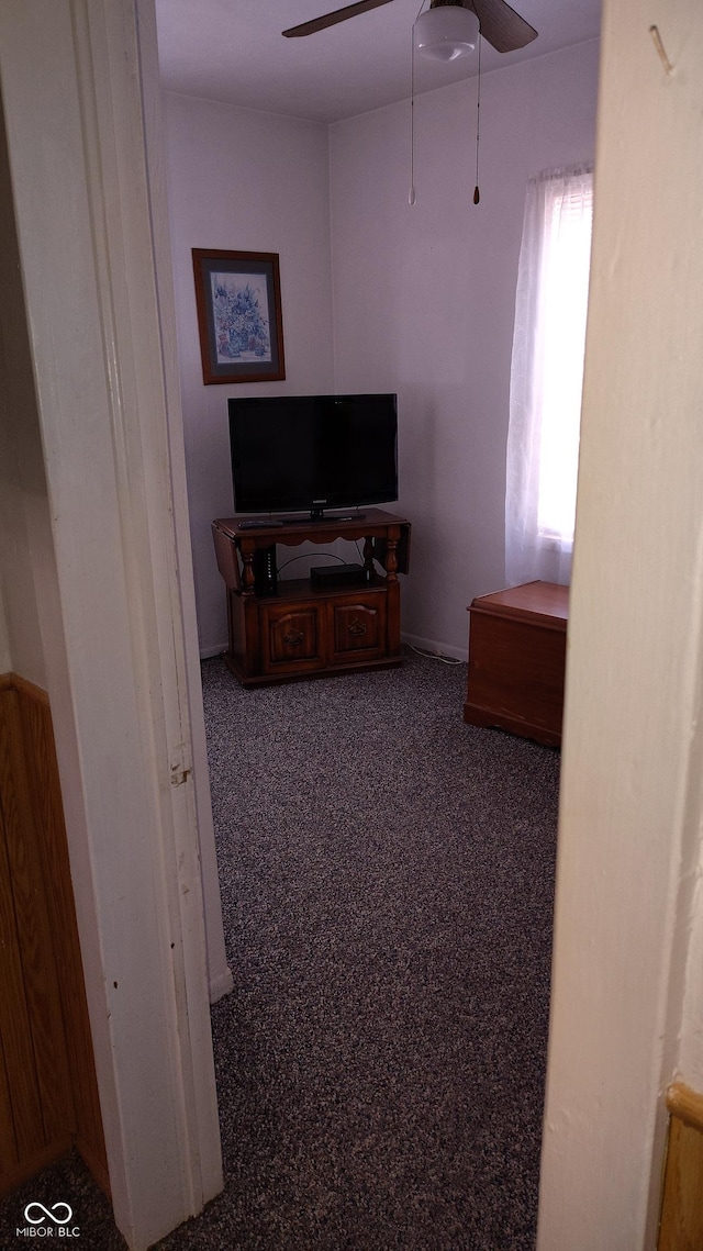 interior space with ceiling fan and dark colored carpet