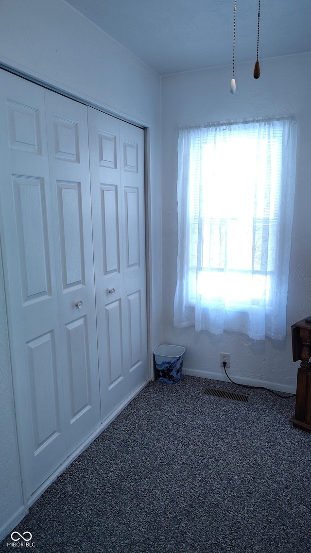 unfurnished bedroom featuring dark carpet and a closet