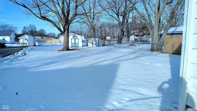 yard layered in snow with a storage shed