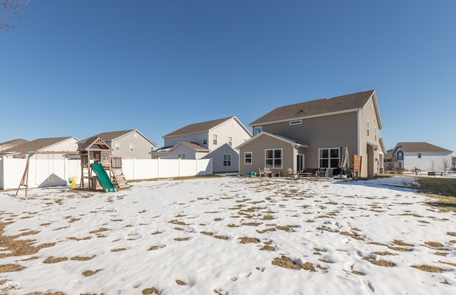 snow covered house with a playground