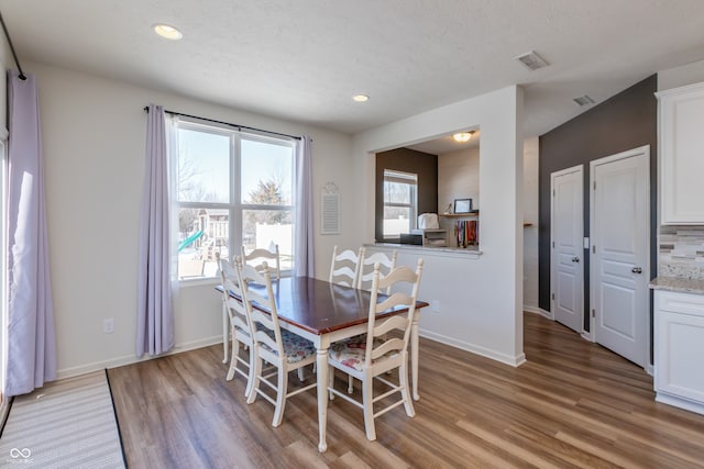 dining area with light hardwood / wood-style floors and a textured ceiling