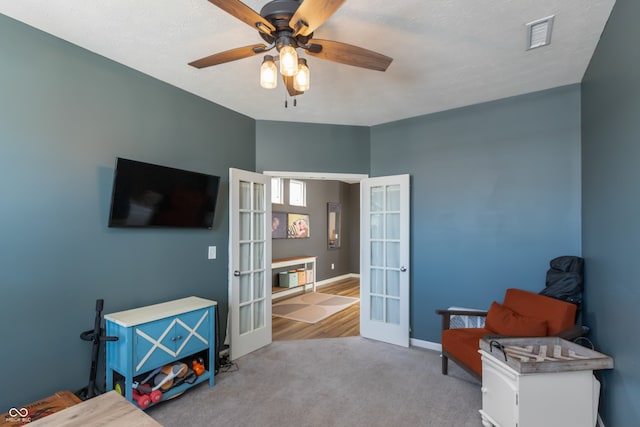 interior space with light carpet, french doors, and ceiling fan